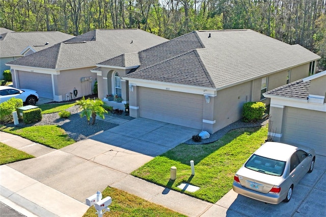 ranch-style house featuring a shingled roof, concrete driveway, stucco siding, an attached garage, and a front yard