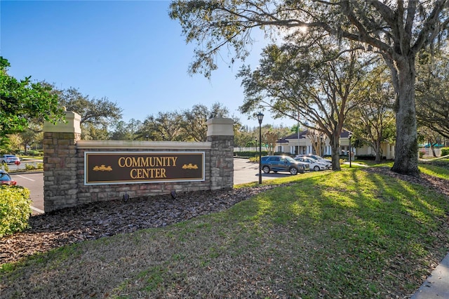 community sign with uncovered parking and a yard