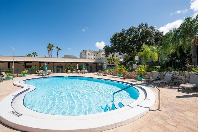 pool with a patio area and fence