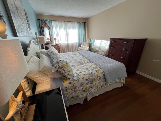 bedroom with a textured ceiling, baseboards, and wood finished floors