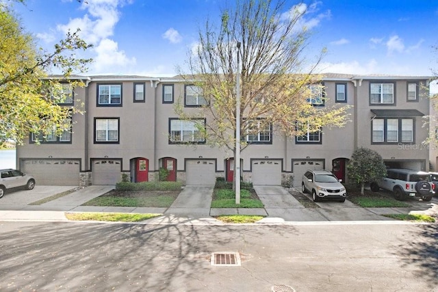 view of front of property with driveway, an attached garage, and stucco siding