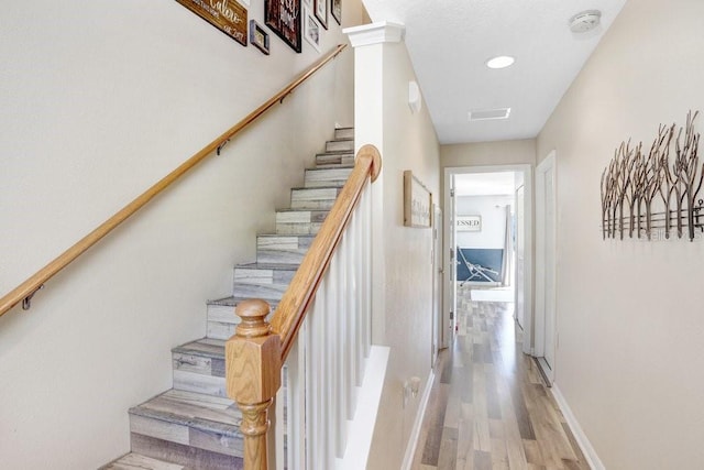 staircase with visible vents, baseboards, and wood finished floors