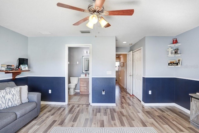 living room with visible vents, ceiling fan, baseboards, and wood finished floors