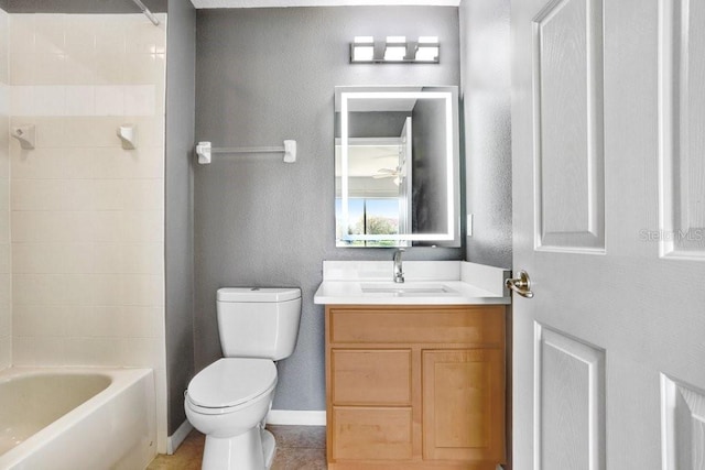 bathroom featuring baseboards, a textured wall, toilet, bathtub / shower combination, and vanity