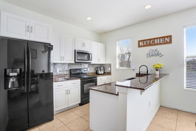 kitchen featuring a peninsula, black appliances, white cabinetry, and a sink