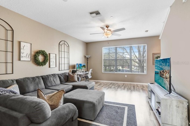 living room with a ceiling fan, baseboards, visible vents, and wood finished floors