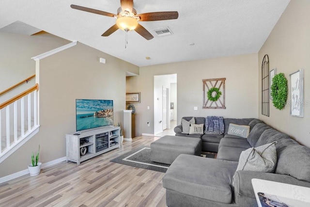 living area featuring visible vents, stairway, light wood-style floors, a ceiling fan, and baseboards