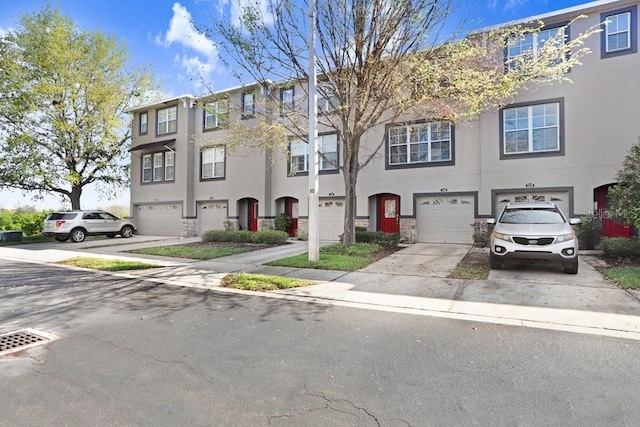 view of property featuring a garage, driveway, and stucco siding