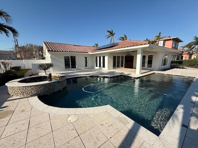 view of swimming pool with a patio area, a fenced backyard, a pool with connected hot tub, and french doors