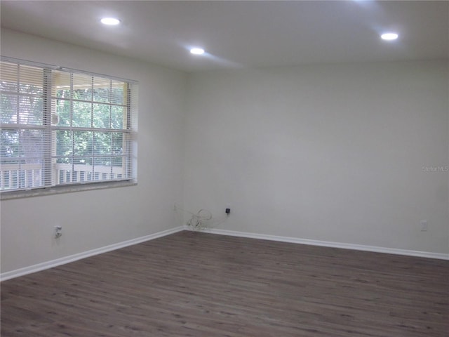 empty room featuring recessed lighting, dark wood finished floors, and baseboards