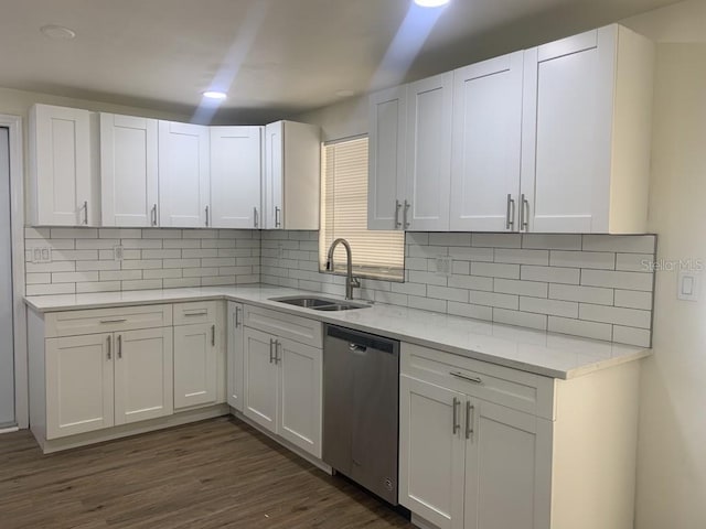 kitchen with dark wood-type flooring, a sink, white cabinetry, stainless steel dishwasher, and tasteful backsplash