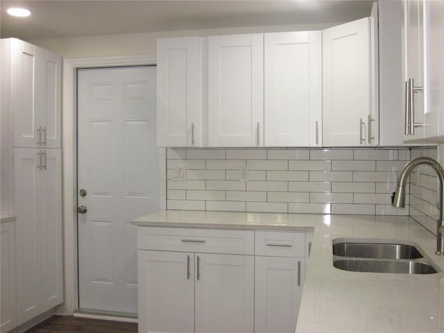 kitchen with white cabinetry, backsplash, and a sink