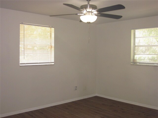 spare room featuring dark wood-style floors, ceiling fan, and baseboards