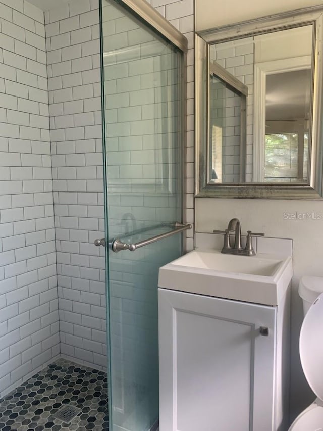 full bath featuring toilet, a stall shower, and vanity