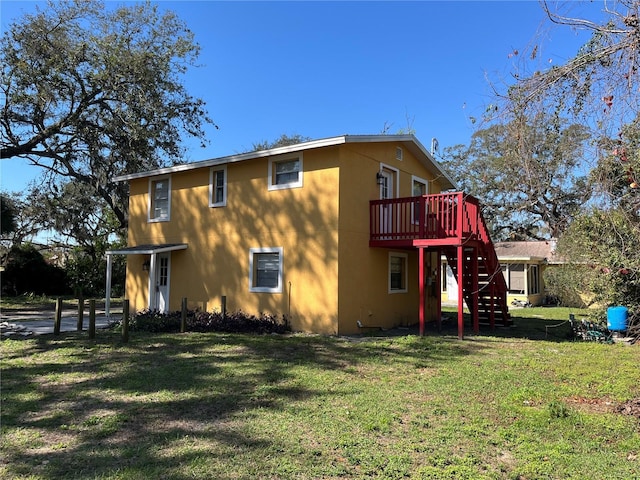 view of home's exterior featuring a deck, a yard, stairway, and stucco siding