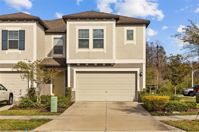 townhome / multi-family property with stucco siding, concrete driveway, and a shingled roof