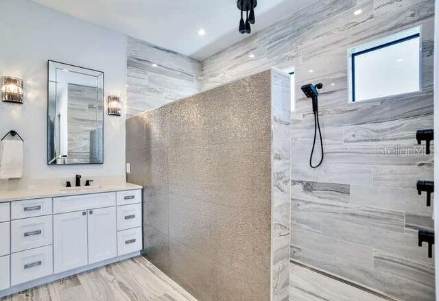 bathroom featuring tiled shower and vanity