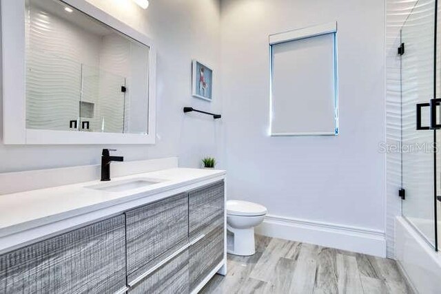 bathroom featuring baseboards, vanity, toilet, and wood finished floors