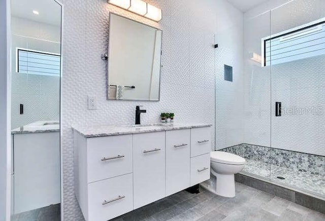 bathroom featuring toilet, a stall shower, and vanity