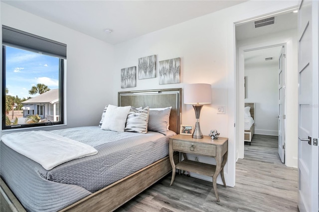 bedroom featuring wood finished floors, visible vents, and baseboards