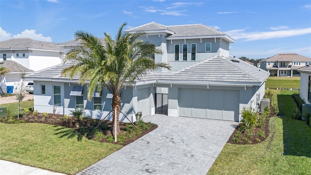 view of front of house featuring a tile roof, an attached garage, decorative driveway, a front yard, and stucco siding