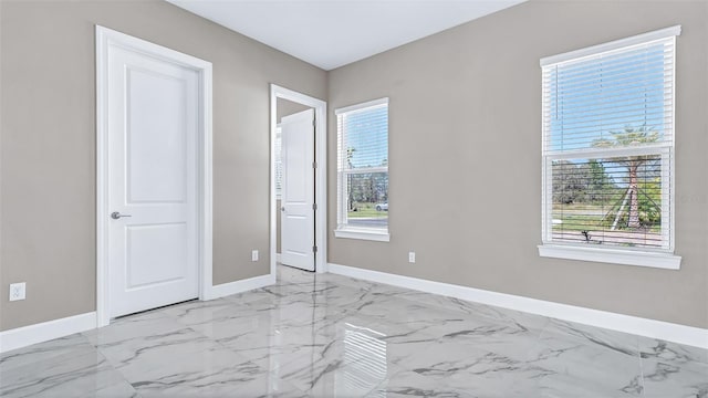 unfurnished bedroom featuring marble finish floor and baseboards