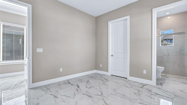 unfurnished bedroom featuring ensuite bathroom, marble finish floor, and baseboards