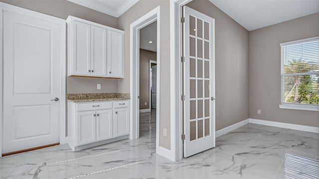 interior space with crown molding, marble finish floor, and baseboards