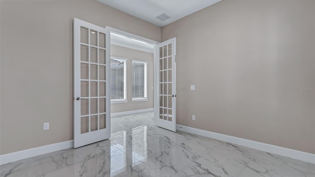 spare room featuring marble finish floor, baseboards, visible vents, and french doors