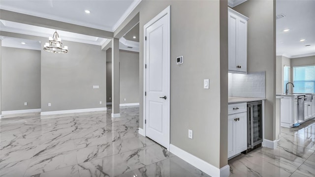 kitchen with beverage cooler, baseboards, marble finish floor, light countertops, and crown molding