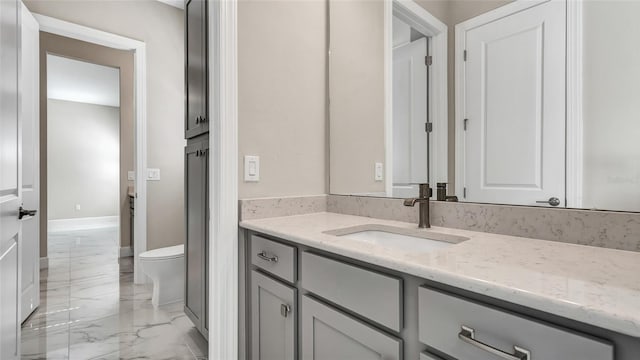 bathroom with toilet, marble finish floor, baseboards, and vanity