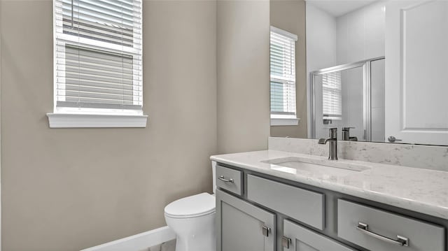 bathroom featuring toilet, a shower stall, baseboards, and vanity