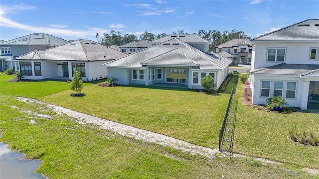 view of front of home featuring a tiled roof, a front yard, fence, and stucco siding