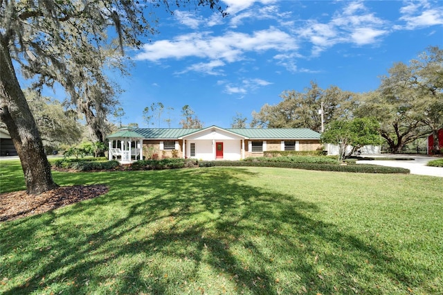 ranch-style home featuring a front yard, a standing seam roof, and metal roof