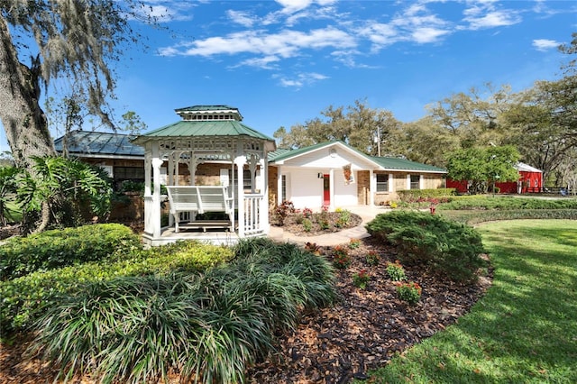 back of property featuring metal roof, a yard, and a gazebo