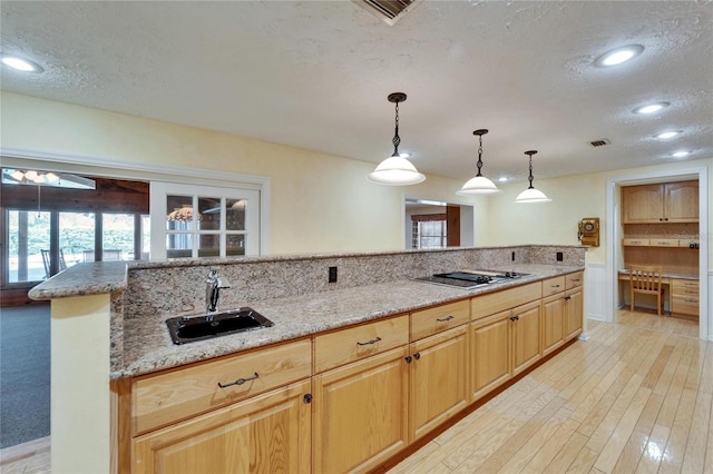 kitchen with visible vents, light stone countertops, black electric stovetop, a textured ceiling, and a sink