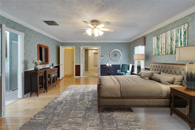 bedroom featuring a textured ceiling, light wood finished floors, visible vents, and wallpapered walls