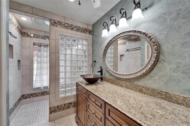 bathroom with vanity, a walk in shower, a textured ceiling, and tile patterned floors