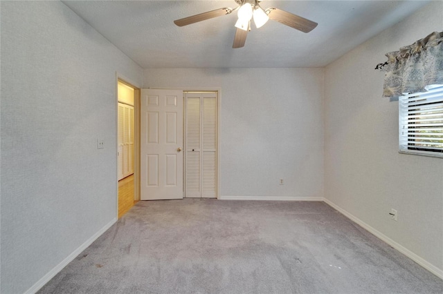 carpeted spare room featuring a ceiling fan and baseboards