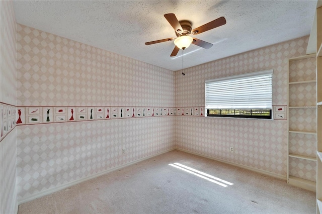 spare room with wallpapered walls, carpet, baseboards, and a textured ceiling