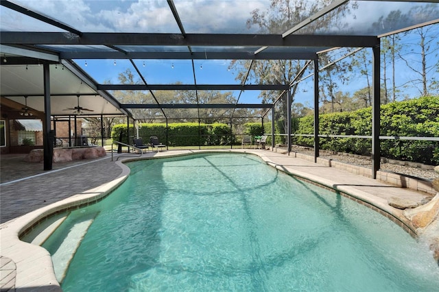 outdoor pool with a lanai, a patio area, and a ceiling fan