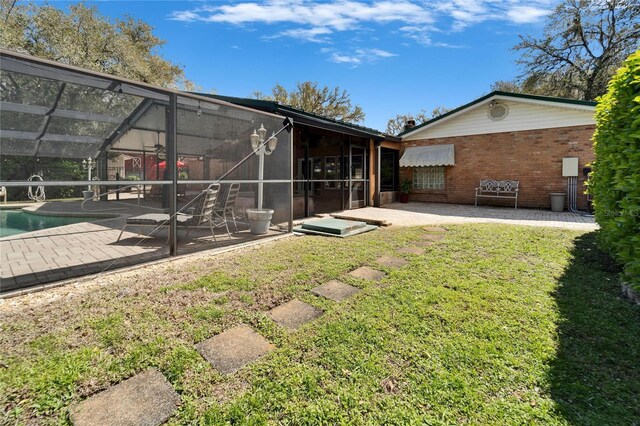 rear view of house featuring brick siding, a patio, a lawn, a lanai, and an outdoor pool