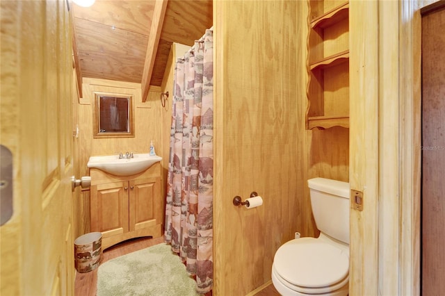 bathroom featuring a shower with shower curtain, wood walls, vanity, and toilet