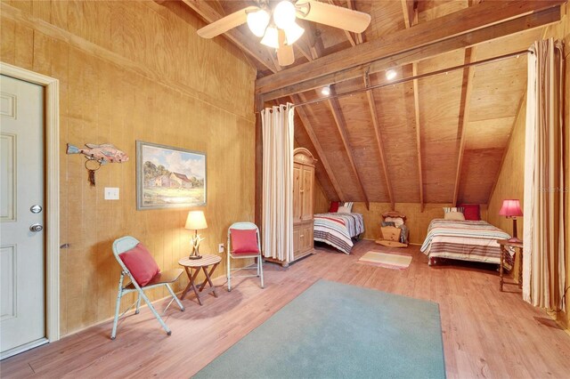 bedroom with vaulted ceiling, a ceiling fan, light wood-style flooring, and wooden walls