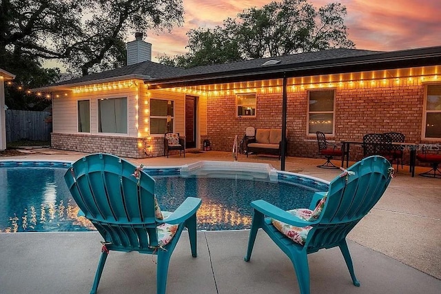 pool at dusk with a patio area, fence, and a fenced in pool