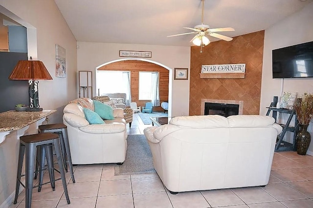 living area featuring a ceiling fan, a large fireplace, and light tile patterned floors