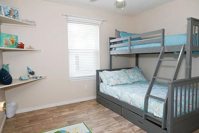 bedroom with a textured ceiling, wood finished floors, and baseboards