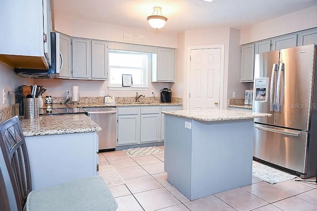 kitchen with a center island, appliances with stainless steel finishes, a sink, and gray cabinetry