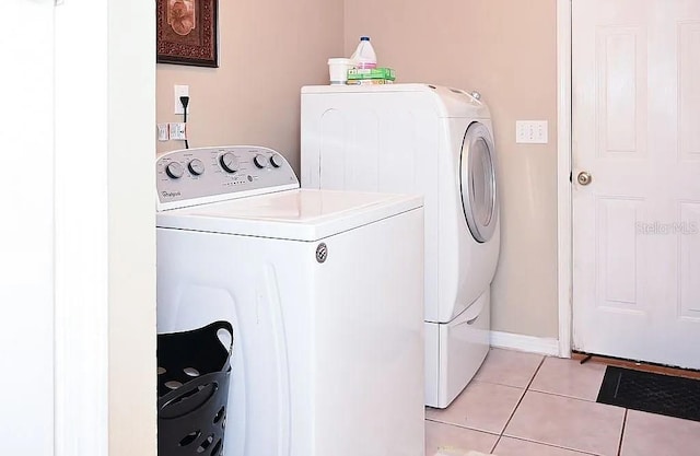 laundry room with laundry area, light tile patterned flooring, washing machine and clothes dryer, and baseboards