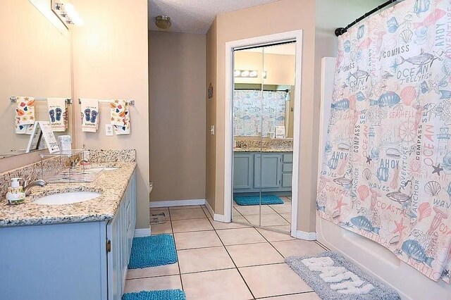 bathroom featuring baseboards, tile patterned floors, a textured ceiling, vanity, and shower / bath combination with curtain